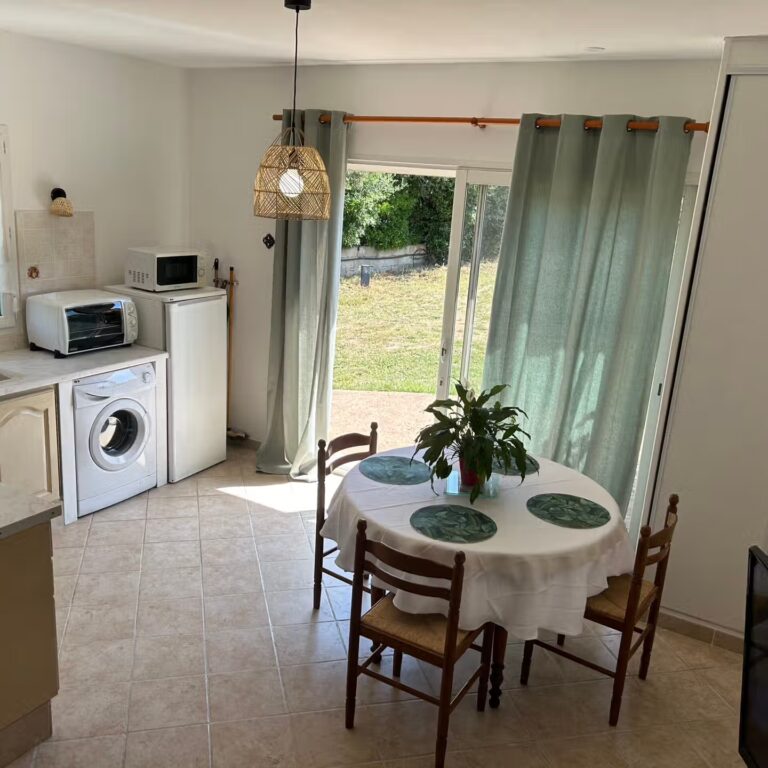 Coin repas et cuisine, baie vitrée ouverte sur le jardin