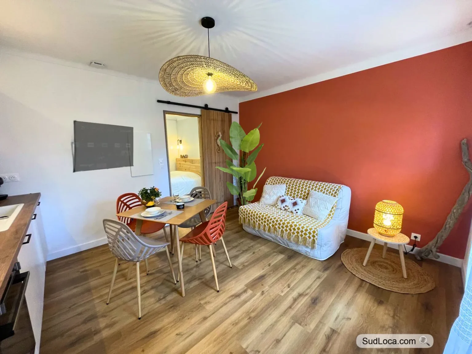 Séjour avec canapé et coin repas devant un mur couleur terre cuite